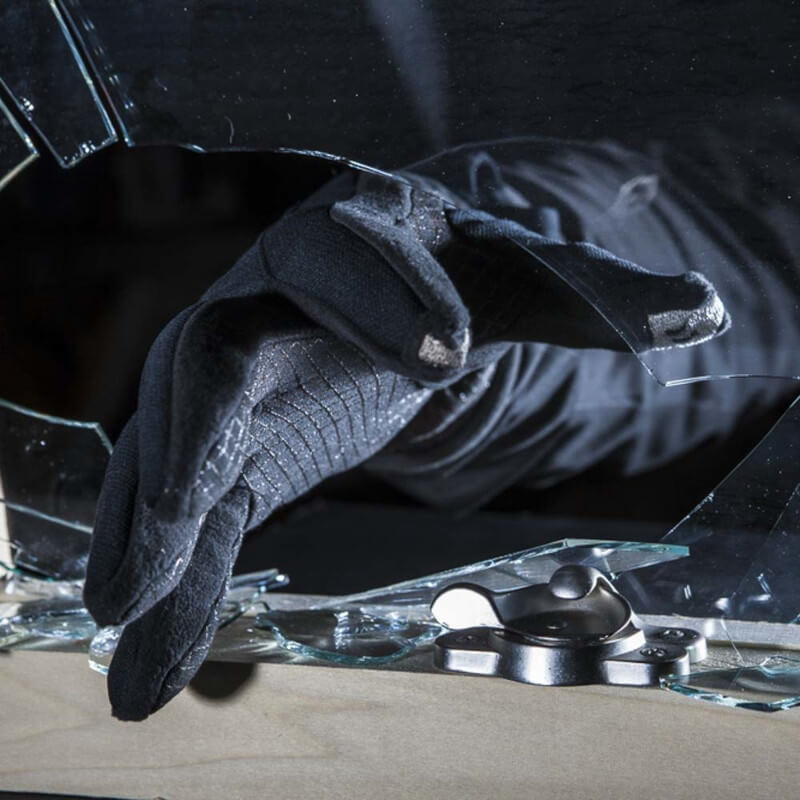 A gloved hand breaking a window.