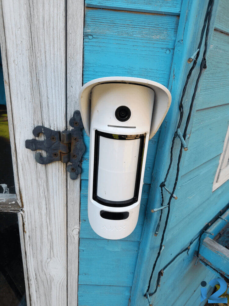 Ajax MotionCam Outdoor on a blue and white shed.