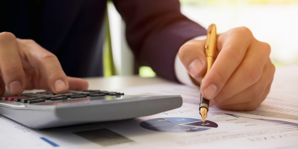 Business professional analysing telecom service costs with financial reports and a calculator.